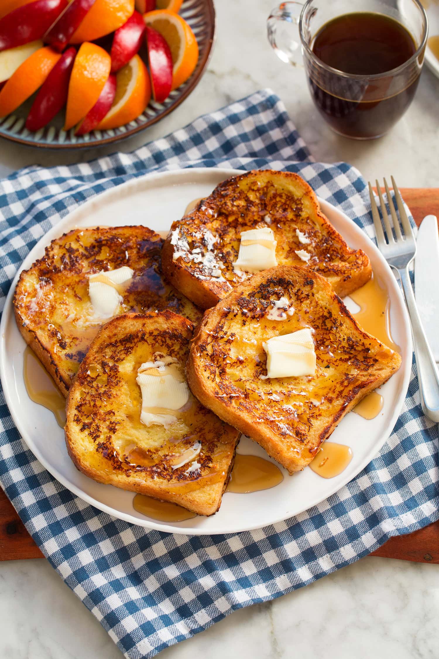 Four slices of buttermilk french toast with butter and maple syrup.