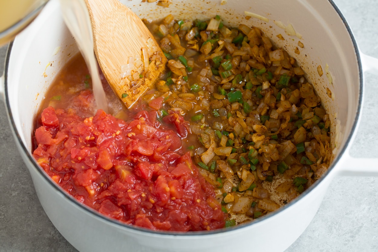 Showing how to make chicken posole. Sauteing veggies, adding broth and tomatoes.