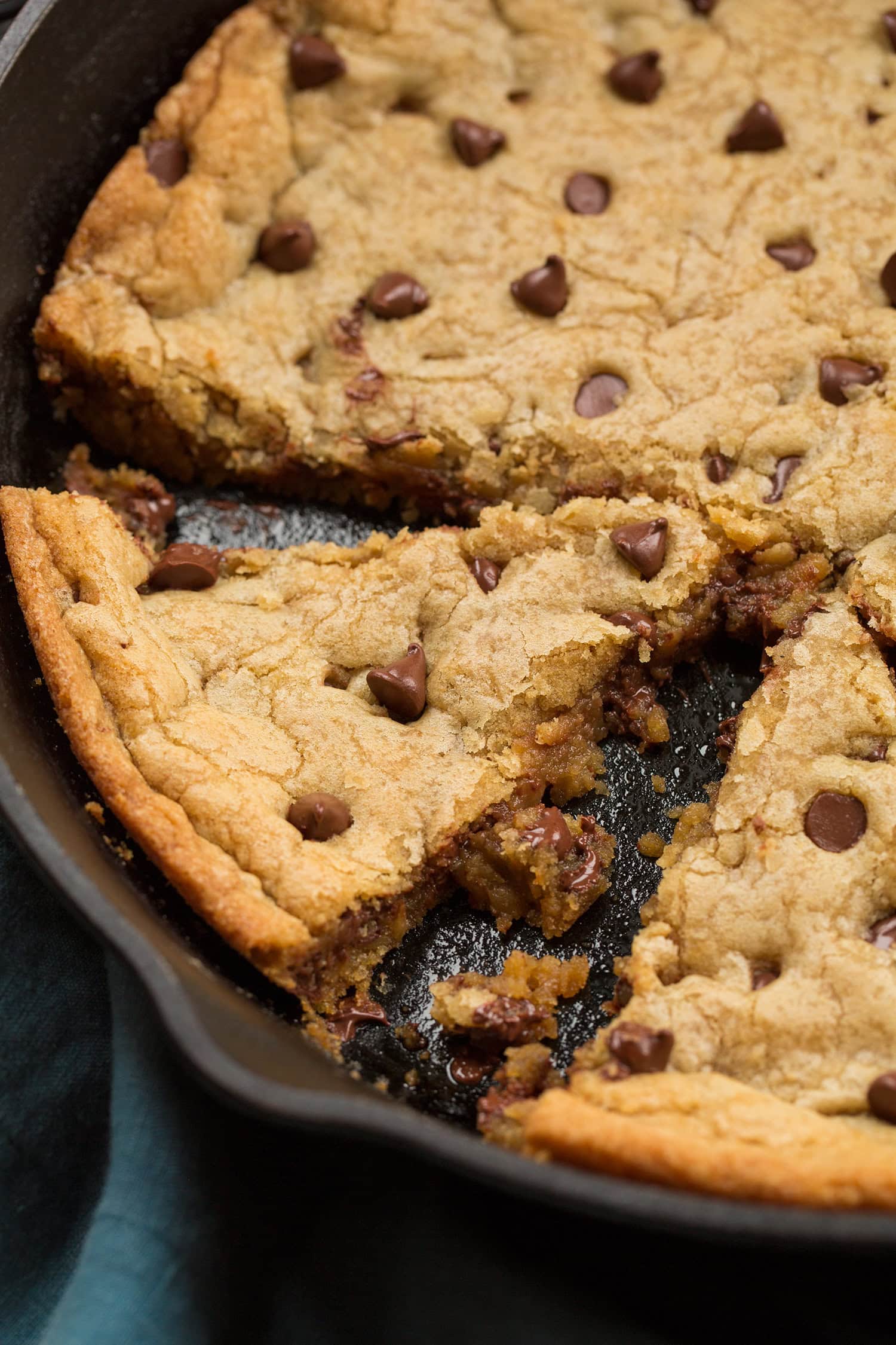 Close up photo showing soft slightly gooey texture of skillet chocolate chip cookie cut into.