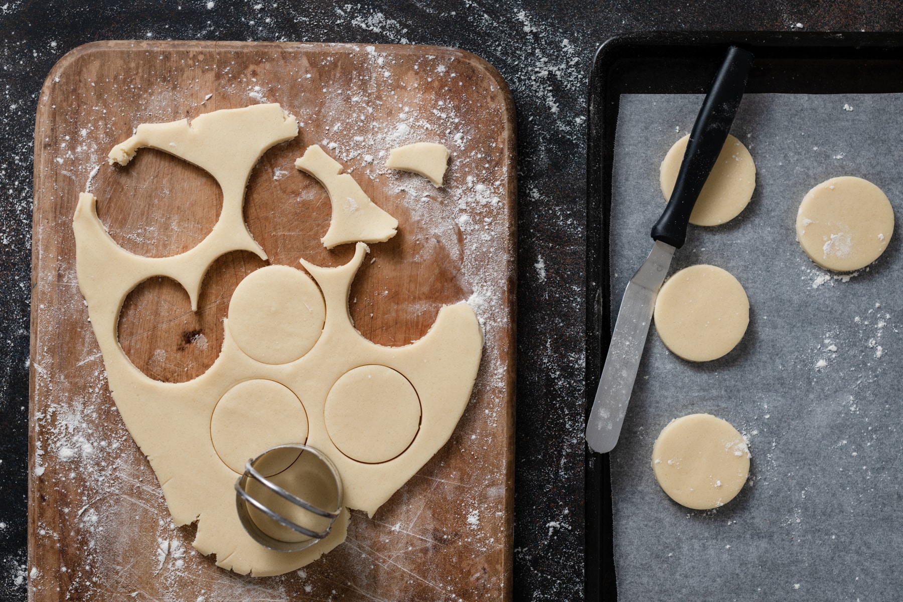 Cutting alfajores cookies into rounds and placing on a baking sheet.