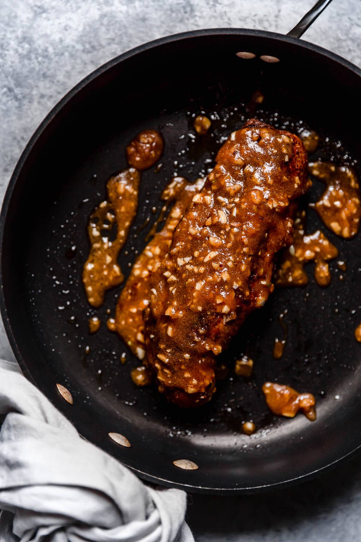 Pork Tenderloin with rub and sauce searing in a large skillet.