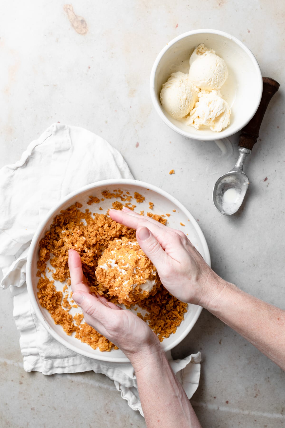 Showing how to make fried ice cream, rolling a ball of ice cream in a cinnamon butter cornflake mixture. 