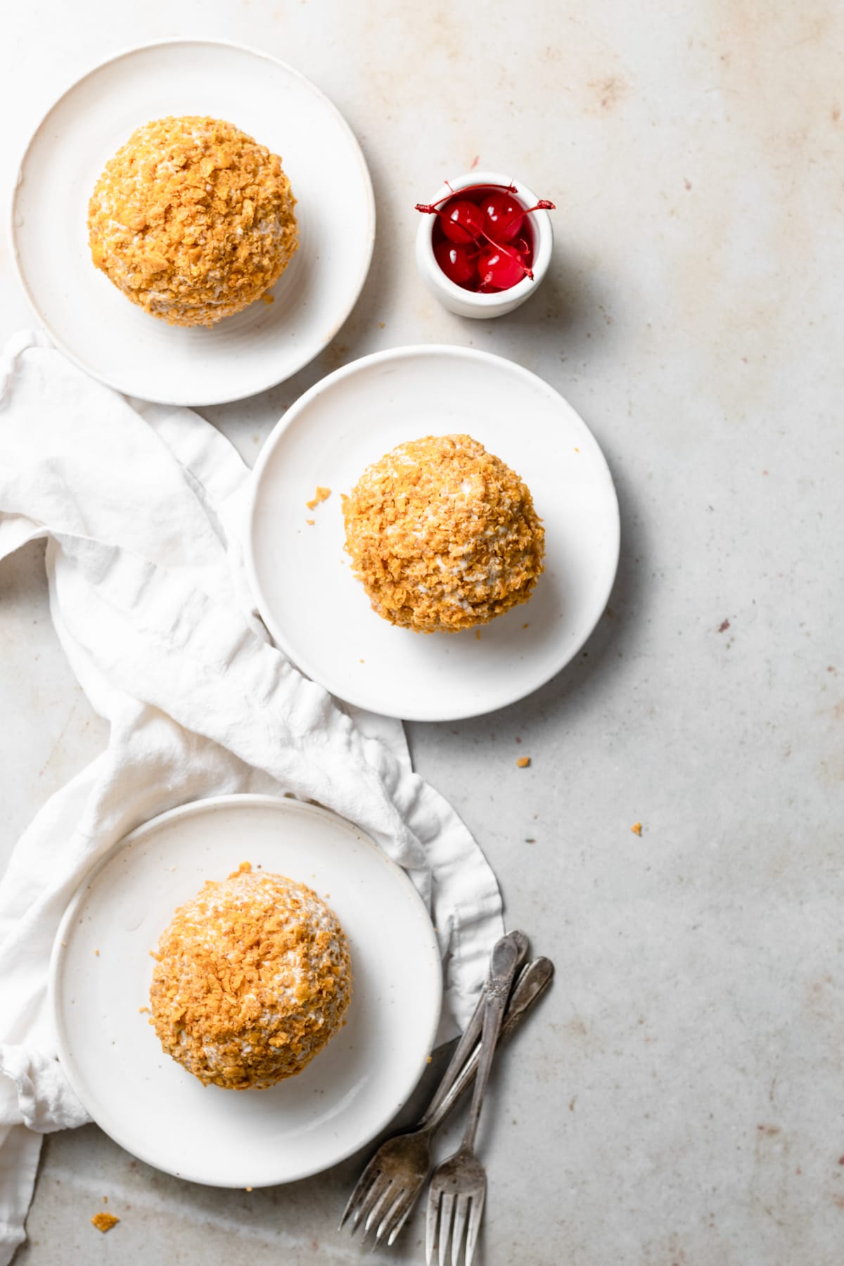 Three fried ice cream balls on a white dessert plates.