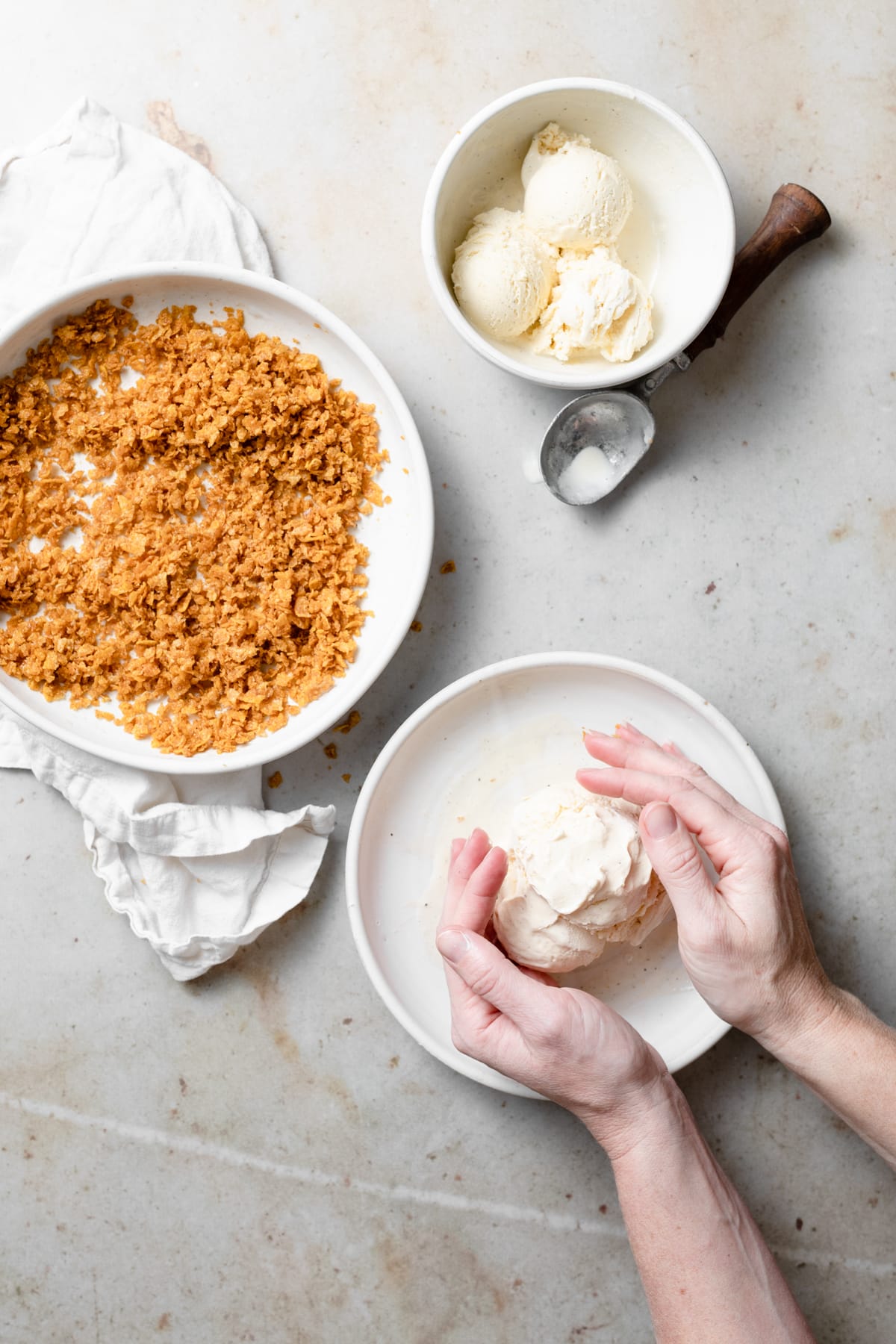 Rolling vanilla ice cream into a ball on a plate.