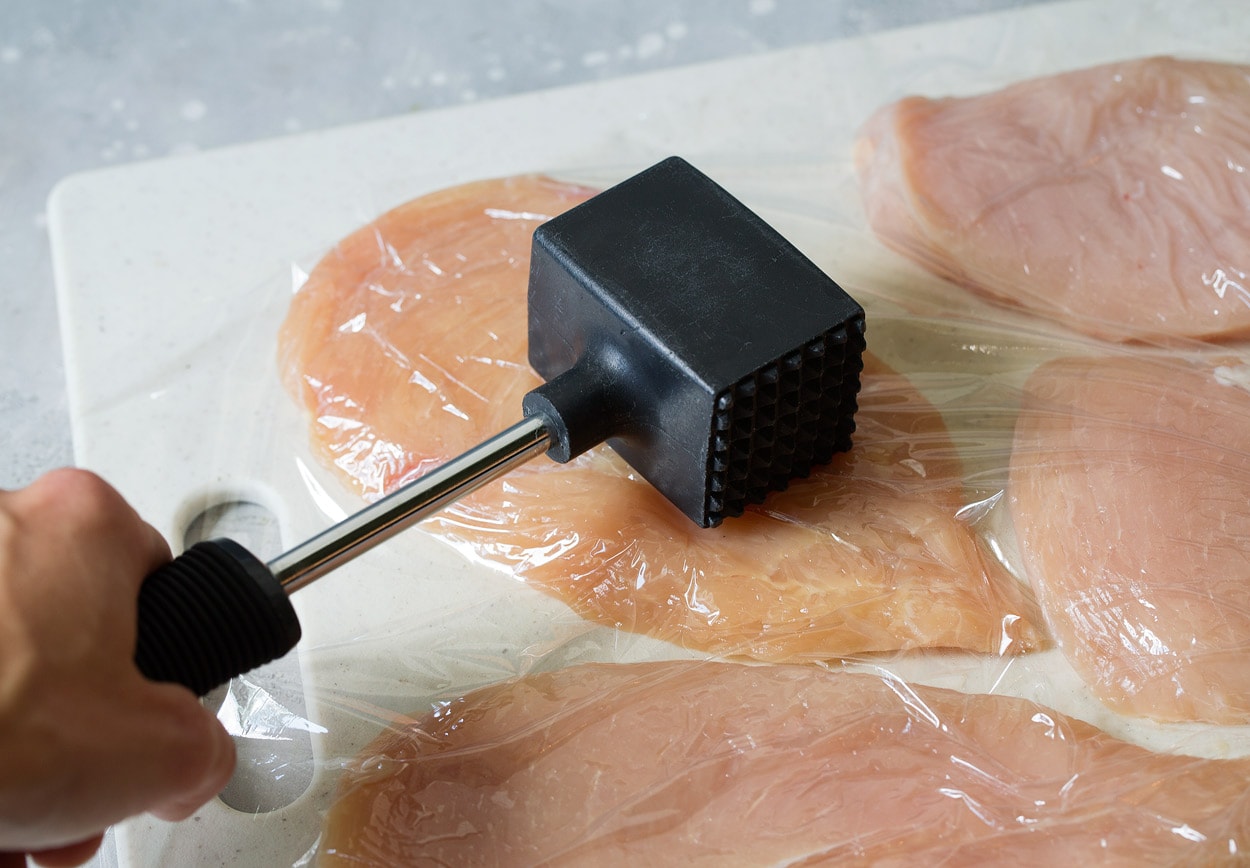 Pounding chicken flat with meat mallet for chicken parmesan.
