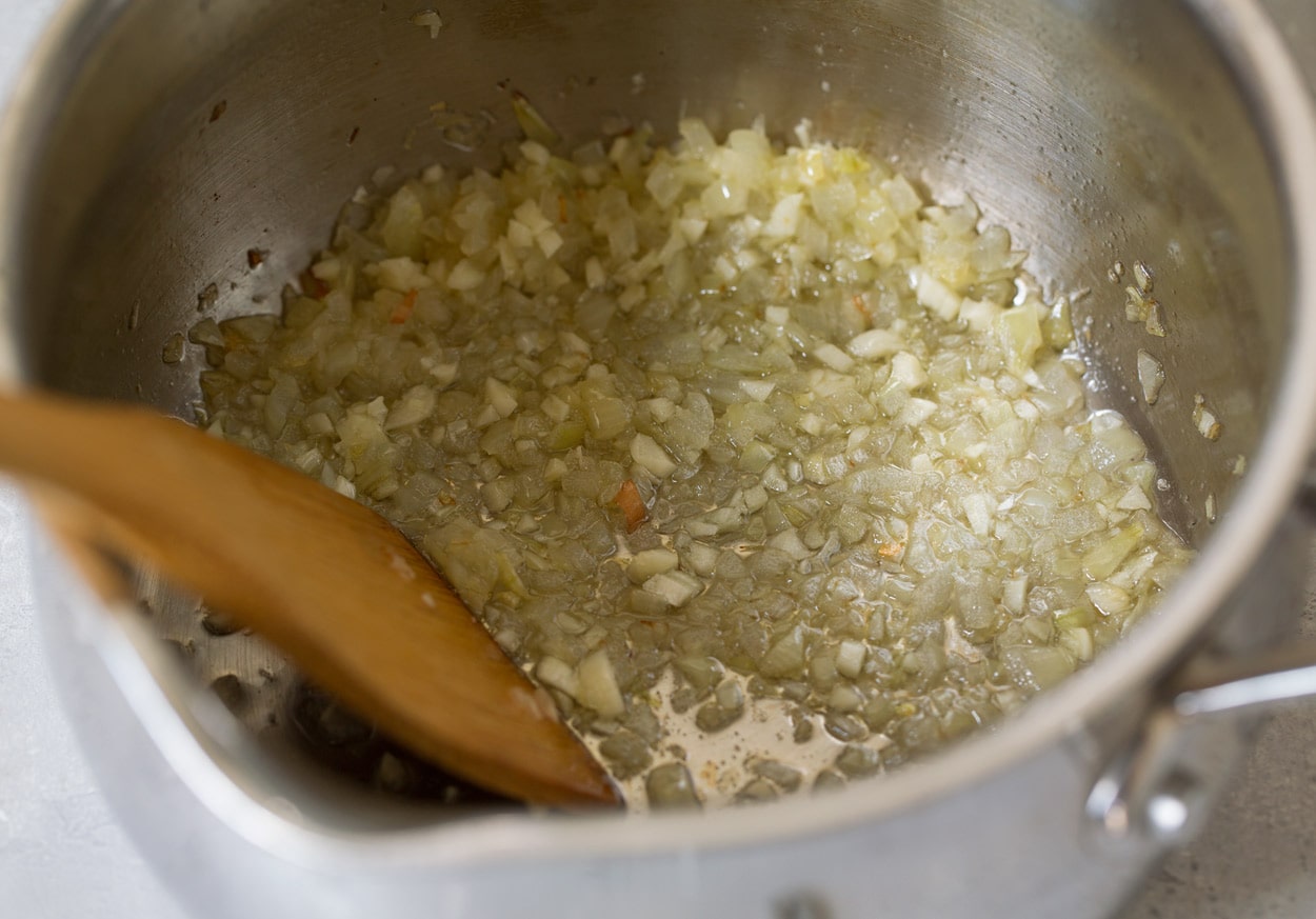 Sauteeing onions and garlic in saucepan for chicken parmesan marinara.