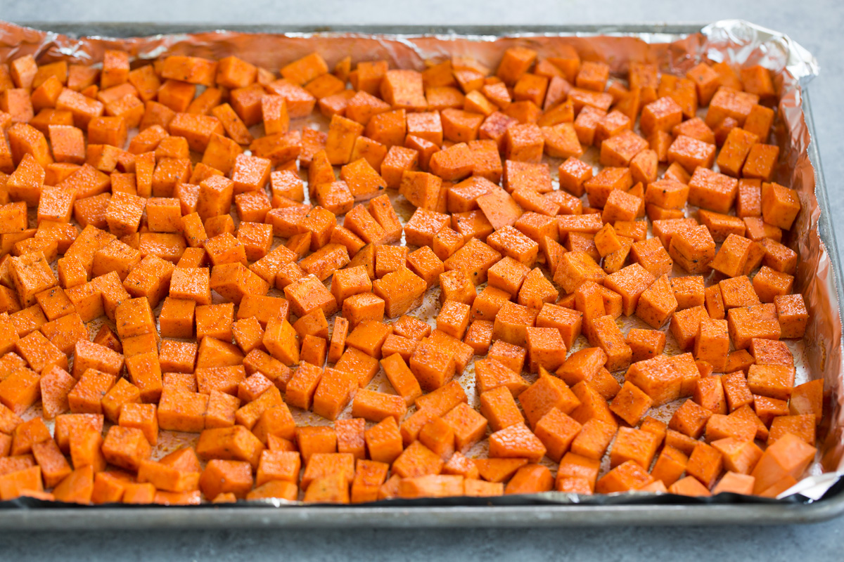 Diced, spiced sweet potatoes on baking sheet before roasting in oven. 