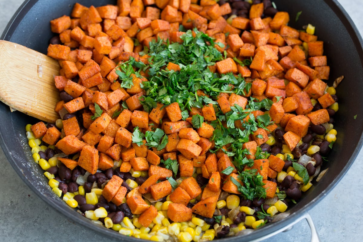 Adding sweet potatoes cilantro to skillet