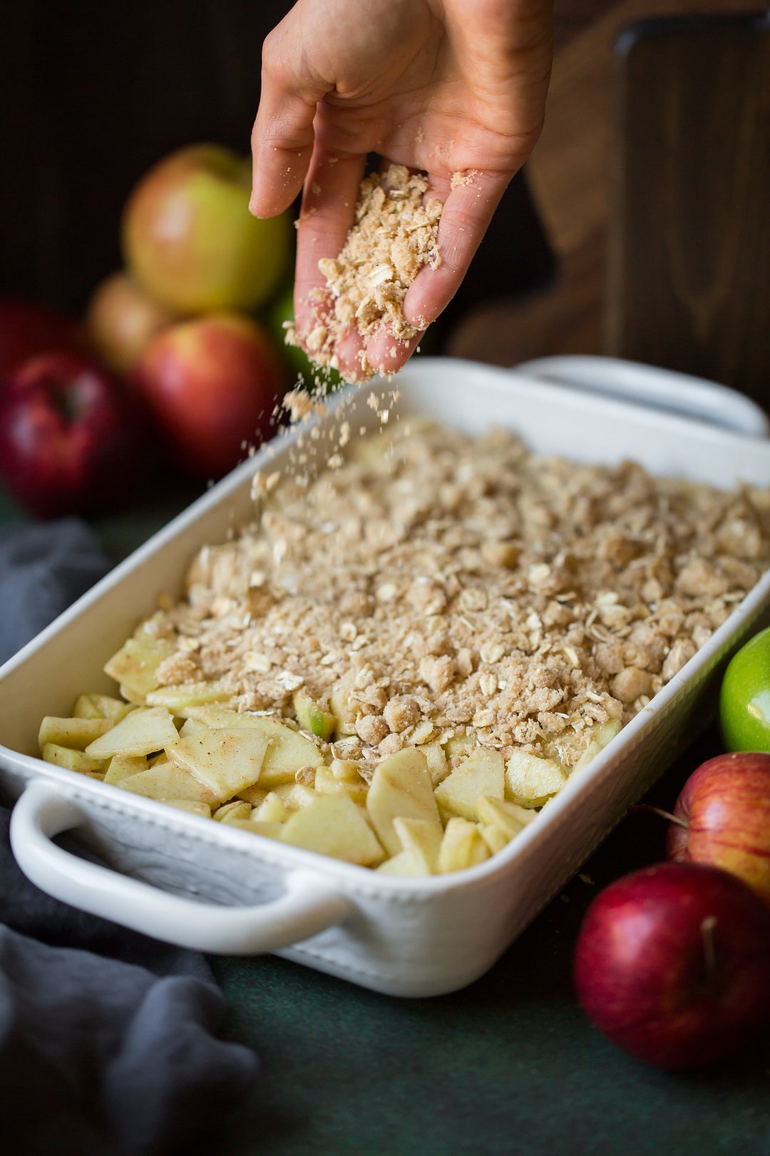 sprinkling apple crisp topping onto sliced apples