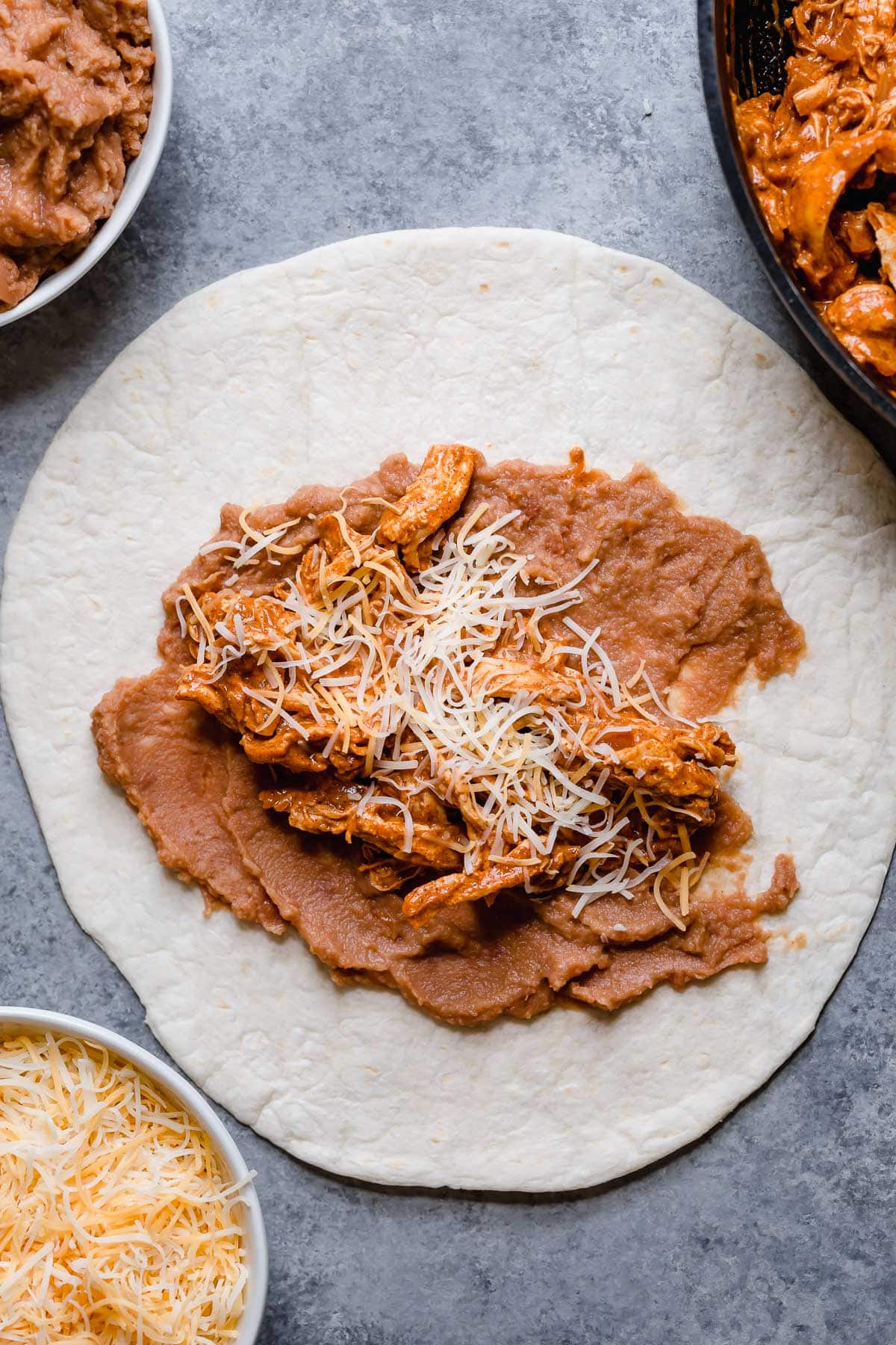 Chicken Chimichangas - one of the ultimate comfort foods! Perfectly hearty and layered with delicious ingredients like seasoned chicken, rich refried beans and shredded Mexican cheese. They're perfectly crisp and oh so satisfying! #chimichanga #chicken #mexican #recipe #refriedbeans #dinnerideas Filled Chicken chimichanga