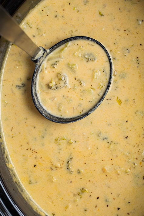The easiest slow cooker Broccoli Cheese Soup recipe! Everyone loves this slow cooker method! So flavorful, so comforting and perfect for cold winter days. | Slow Cooker Soup | Cheese Soup | Broccoli Soup | #cookingclassy #broccoli #cheese #soup #slowcooker Slow Cooker Broccoli Cheese Soup in a slow cooker with a ladle
