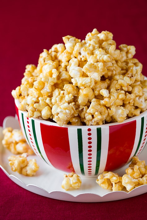 Mound of caramel popcorn in a serving bowl over a white platter.