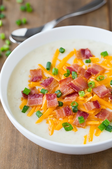 This comforting slow cooker loaded potato soup is perfect on those chilly winter nights. So easy to prepare and full of flavor! #cookingclassy #soup #potato #slowcooker Slow Cooker Loaded Potato Soup in a white bowl topped with bacon, cheese and green onions