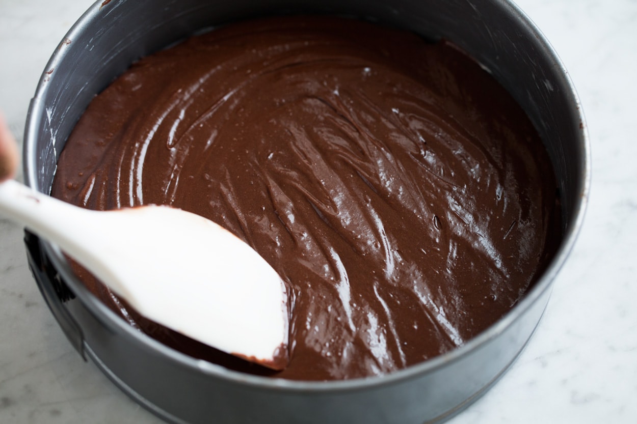 Spreading flourless chocolate cake batter into a 9-inch springform pan.