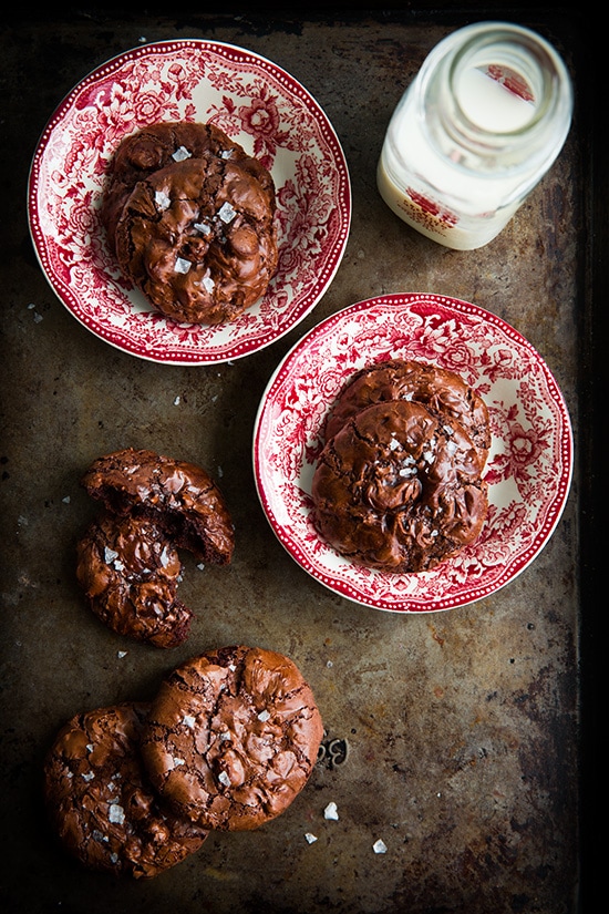 Flourless Chocolate Cookies on red and white plates next to a glass of milk
