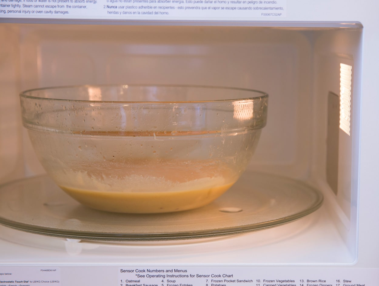 Heating butter, sugar, condensed milk mixture in glass mixing bowl in microwave to make caramels.