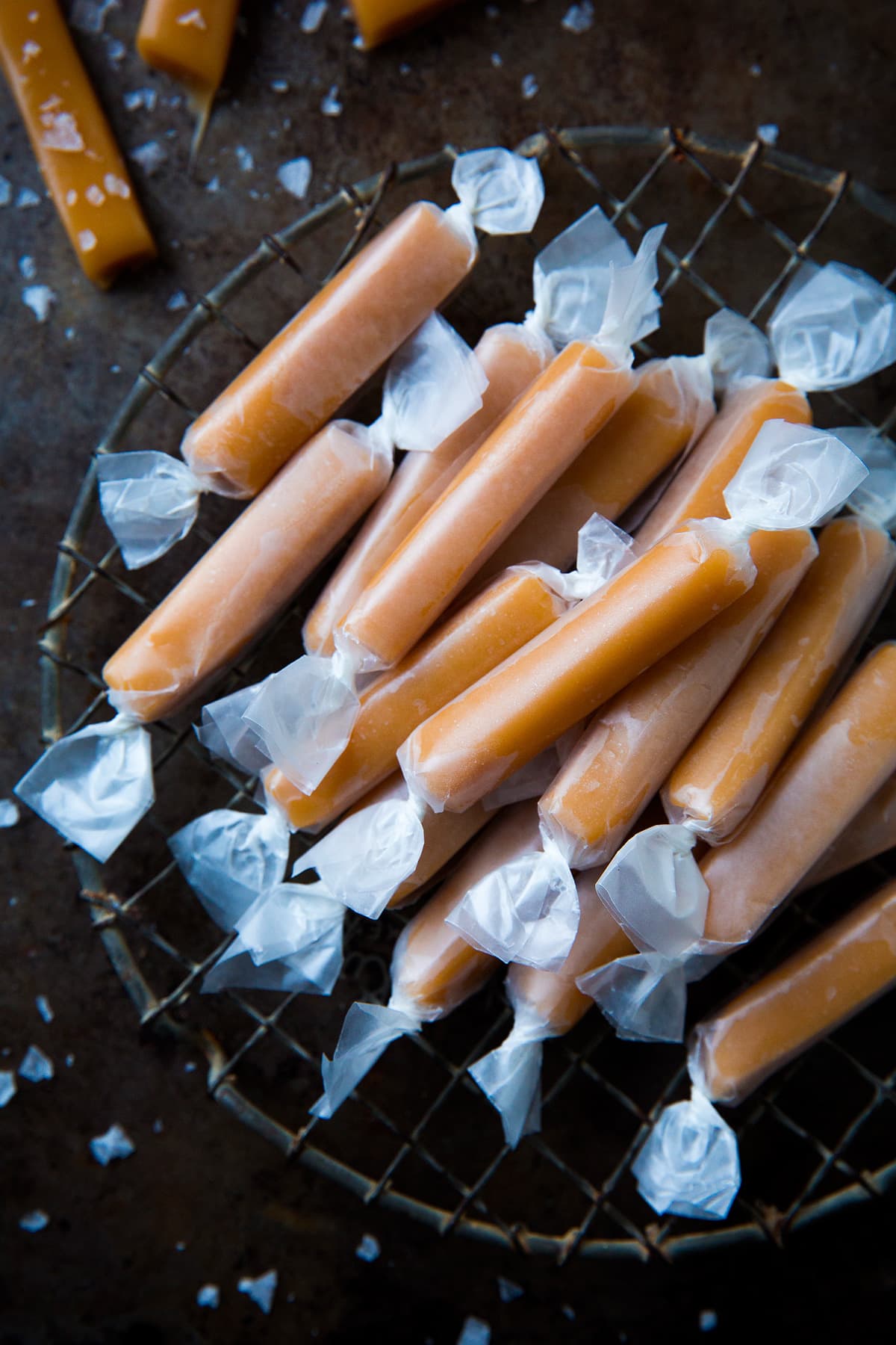 Stack of caramels wrapped in wax paper set over a vintage cooling rack and baking pan.