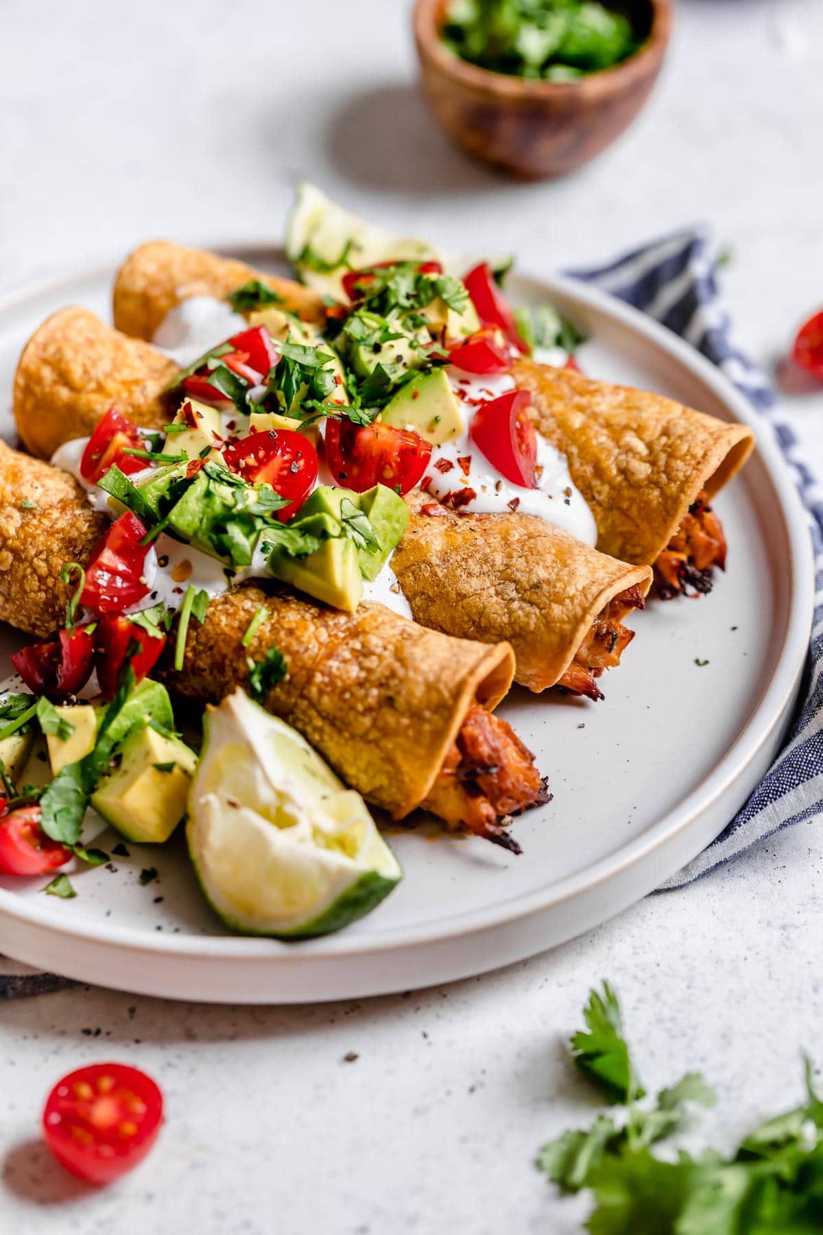 Baked Chicken Taquitos Close up image of taquitos on a white serving plate.