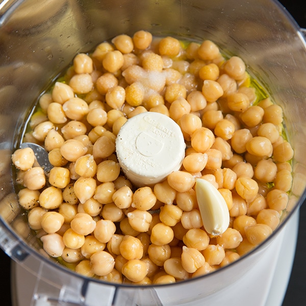 This creamy delicious homemade hummus recipe is the best! It can be made in under 10 minutes and it makes the perfect midday snack for you and your family, or take it to a party and impress your friends! #cookingclassy #hummus #avocado #dips Garlic and chickpeas in a food processor