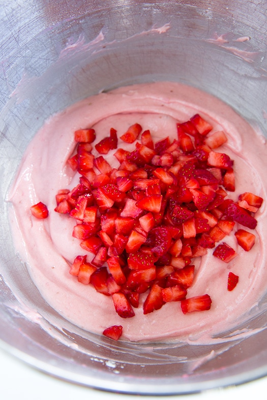 These Strawberry Cupcakes are made with chunks of fresh strawberries in the cake batter and are topped with a luscious pink Strawberry Buttercream Frosting. Bursting with flavor, these cupcakes would go down a treat at any celebration! #cookingclassy #cupcakes #strawberry #buttercream #cakes An overhead shot of strawberry cupcake batter in a bowl with fresh diced strawberries