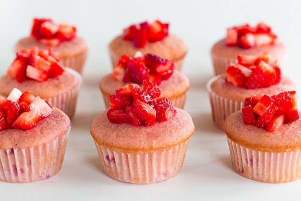 These Strawberry Cupcakes are made with chunks of fresh strawberries in the cake batter and are topped with a luscious pink Strawberry Buttercream Frosting. Bursting with flavor, these cupcakes would go down a treat at any celebration! #cookingclassy #cupcakes #strawberry #buttercream #cakes A process shot of filling strawberry cupcakes with fresh strawberries