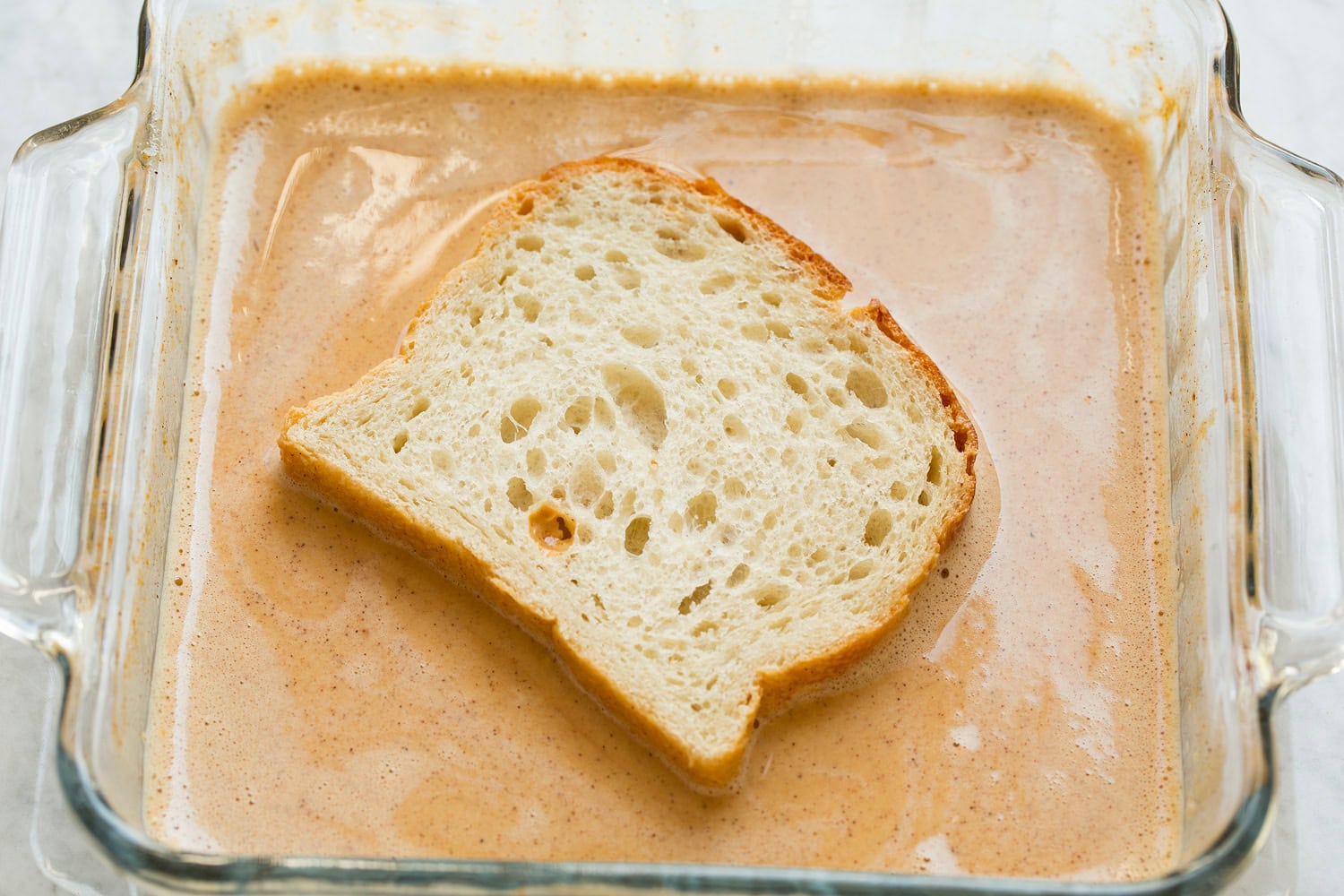 French bread shown dipped in pumpkin egg custard on first side.