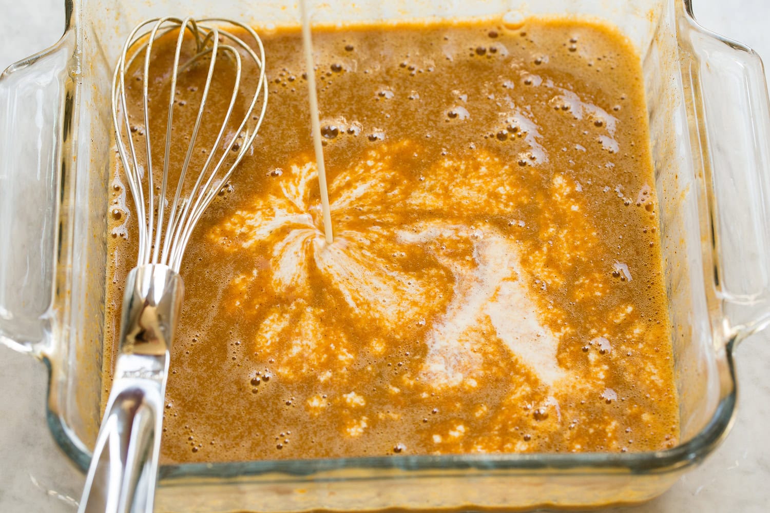 Pumpkin, eggs, spices, sugar shown mixed and half and half being added.