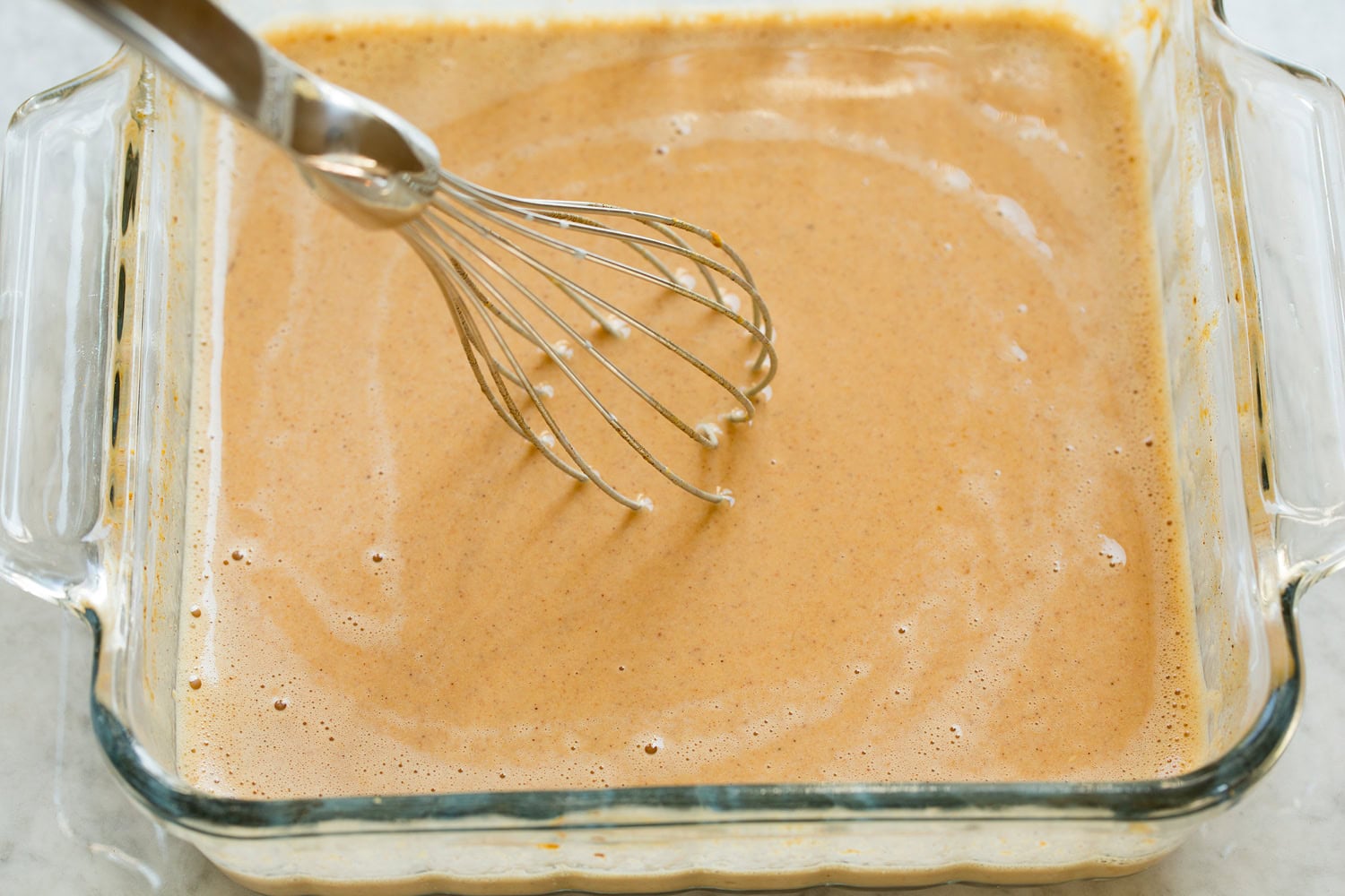 Finished custard mixture for pumpkin french toast in glass dish.