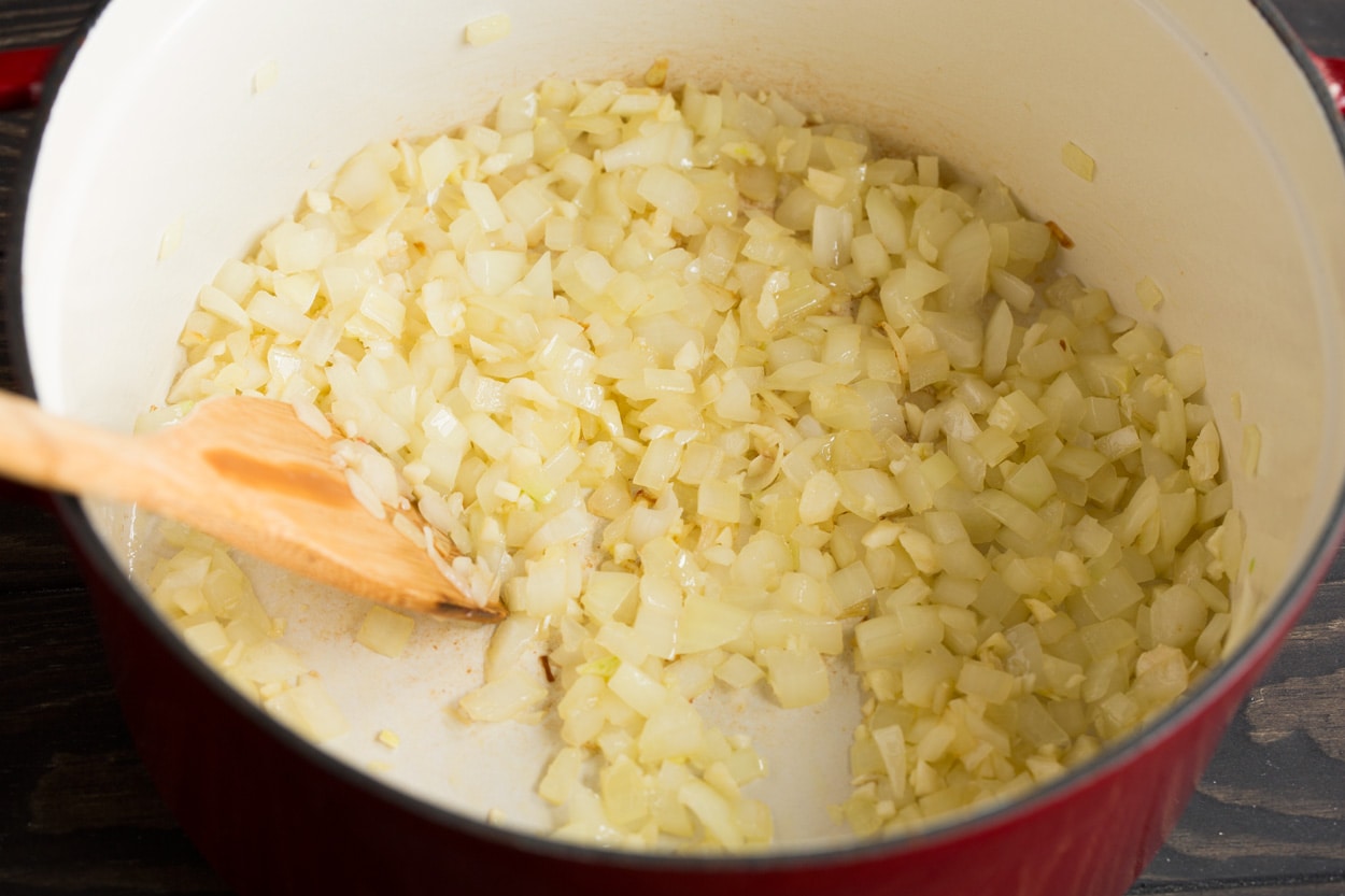 Showing how to make tortellini soup. Starting by sauteeing onion and garlic in a large pot.