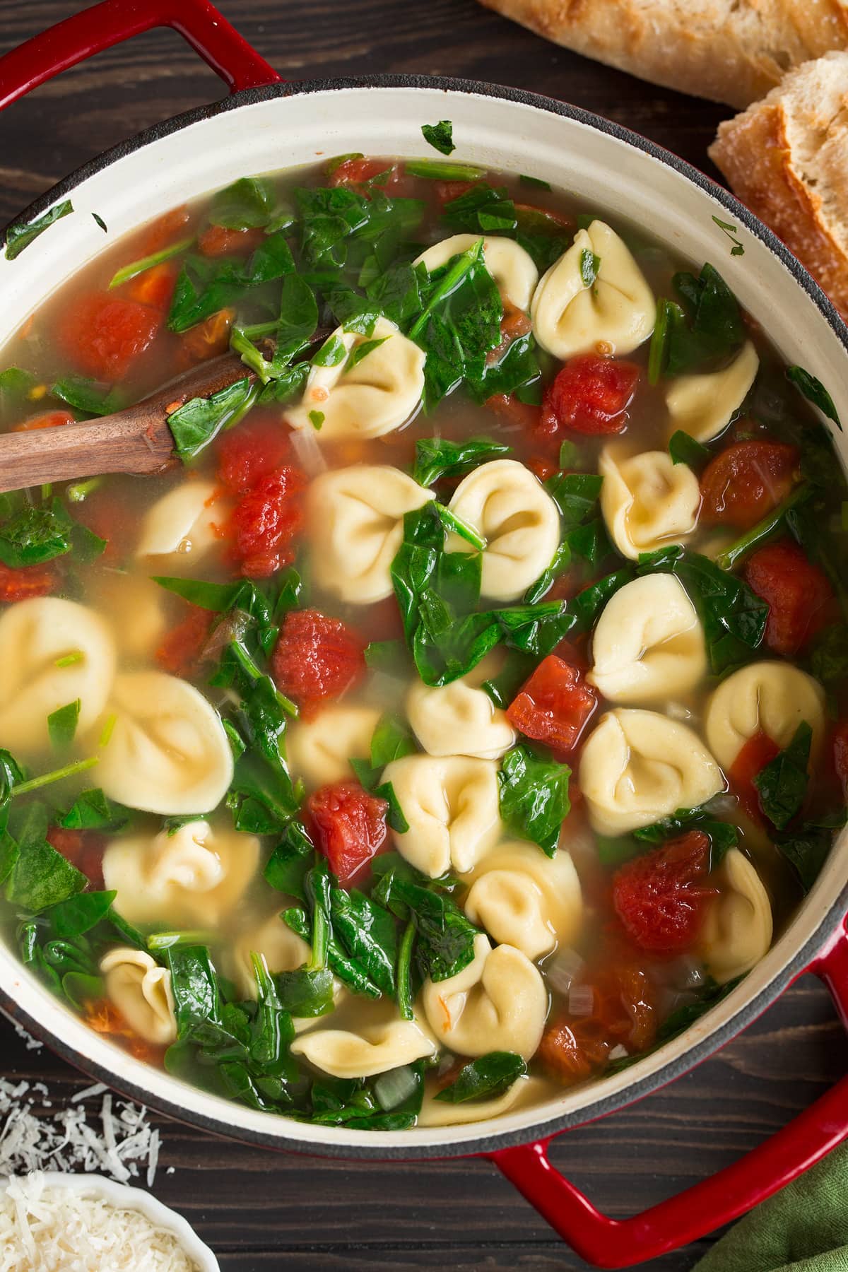 Overhead image of tortellini soup in a large red pot.
