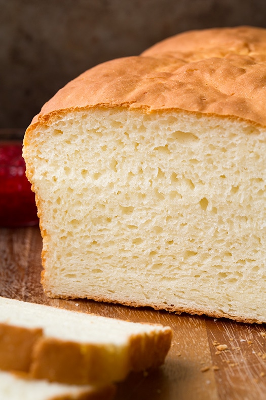Gluten Free Bread shown here on a wood cutting board up close with two slices cut