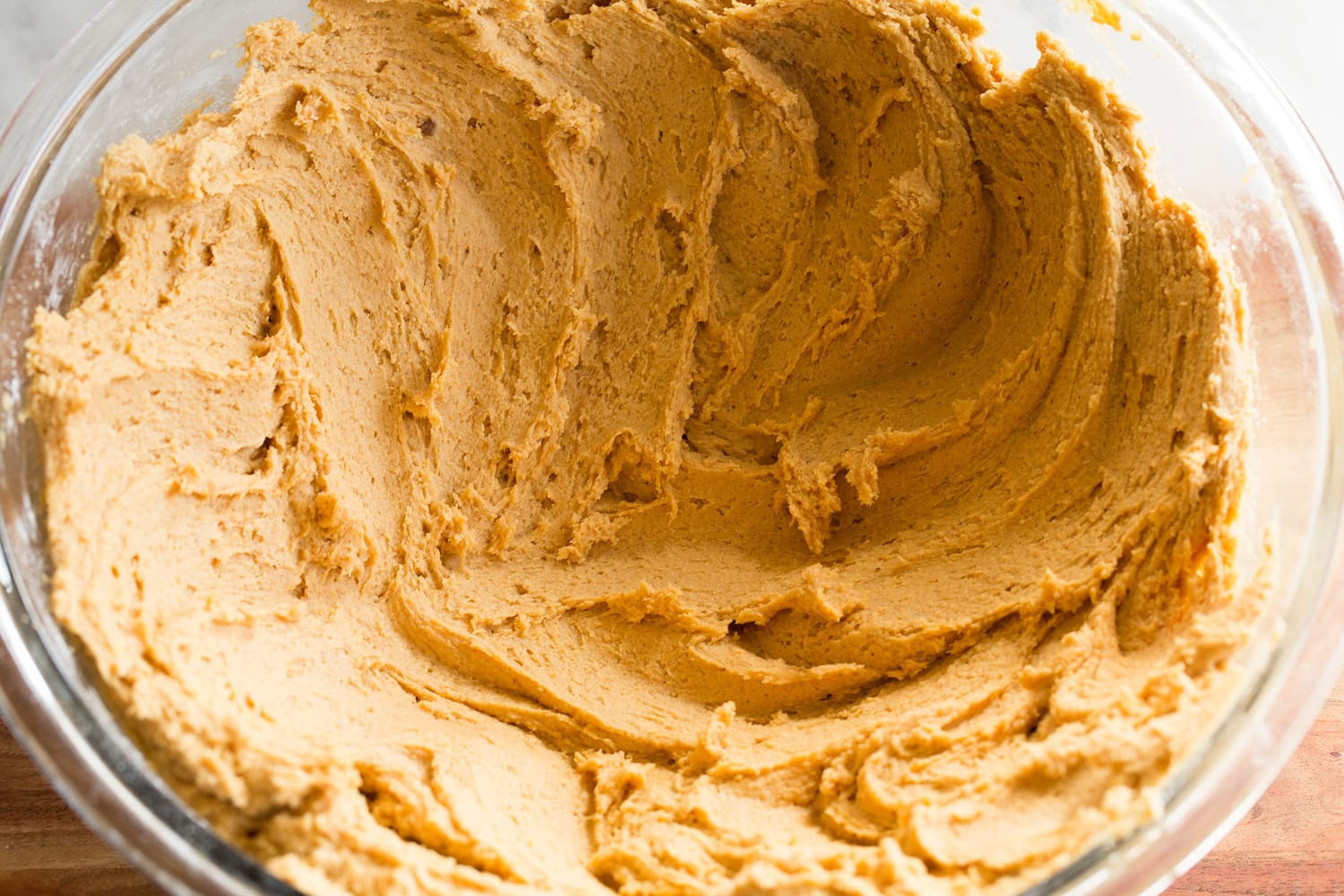Pumpkin cookie dough spread out in bowl to chill evenly.