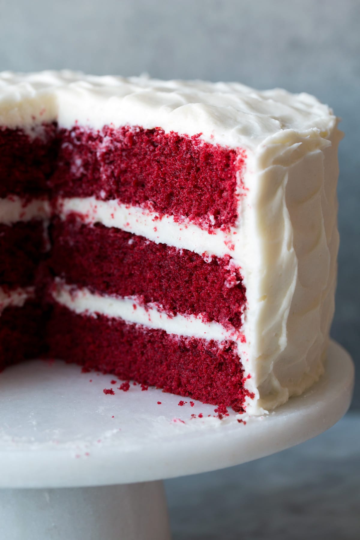 Red Velvet cake with a slice removed to show interior of cake. Cake is resting on a cake stand.