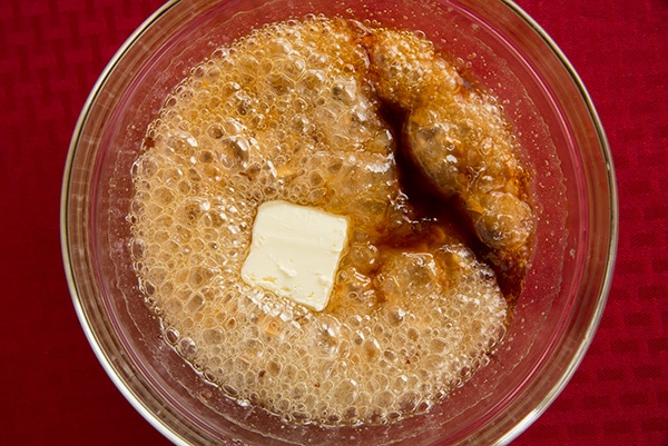 Adding butter and vanilla mixture in mixing bowl.