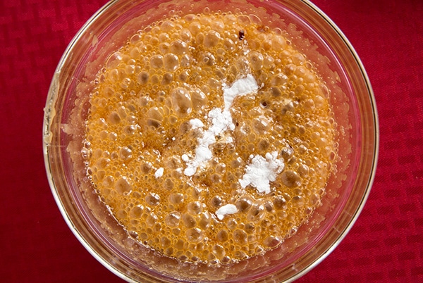 Adding baking soda to mixture in mixing bowl.