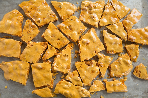 Breaking peanut brittle into pieces after cooling.