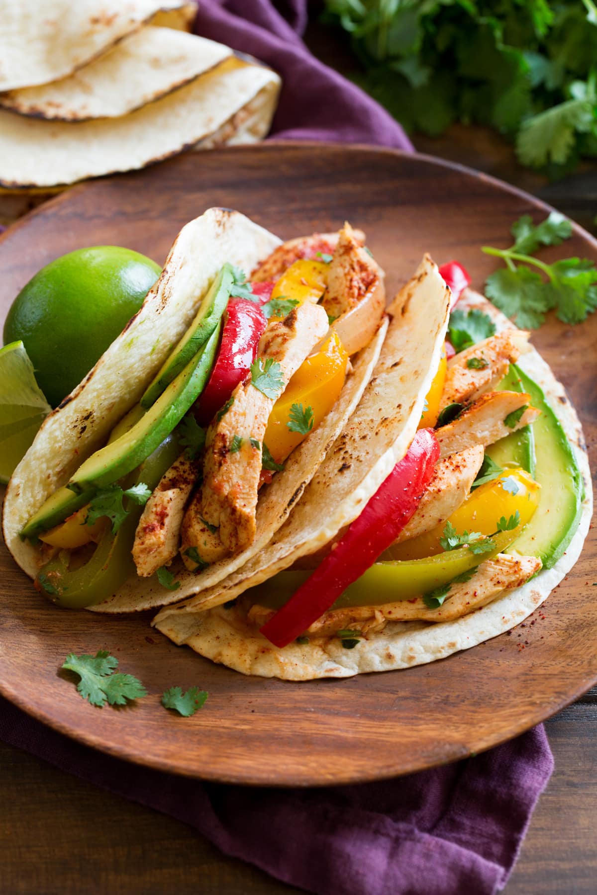 Two chicken fajitas on a wooden plate.