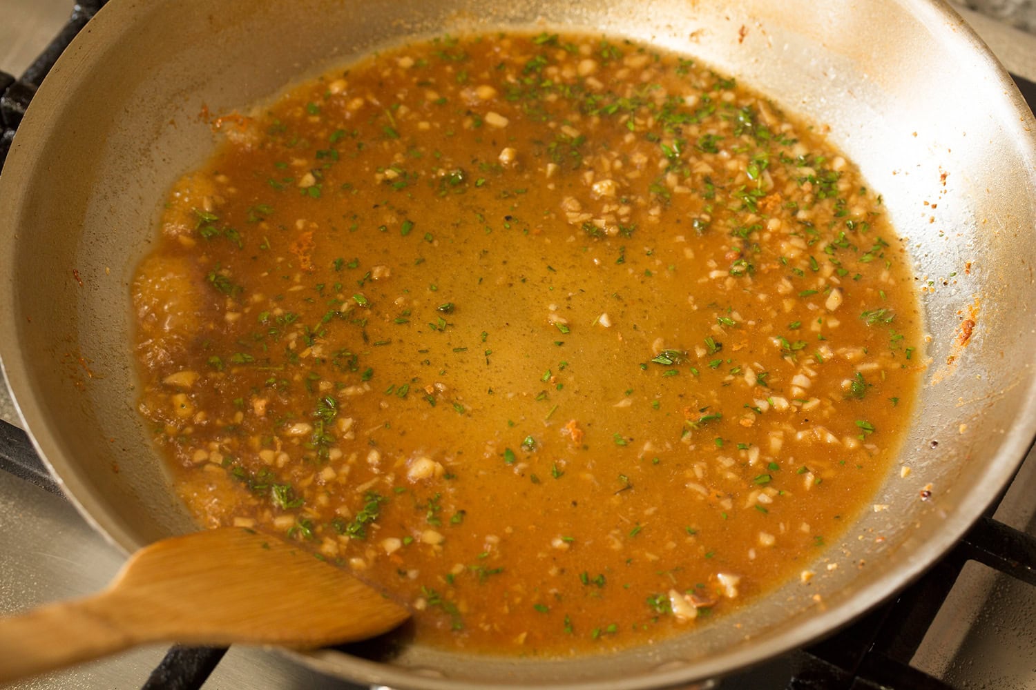 Chicken broth and herbs added to sauteed garlic in skillet.