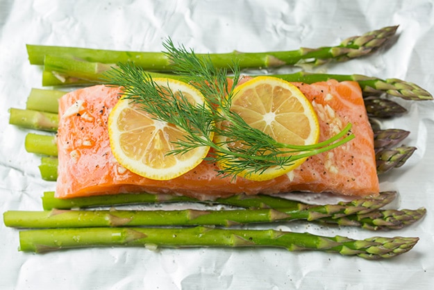 Baked Salmon and Asparagus in Foil Adding lemon slices and fresh dill over salmon fillet.