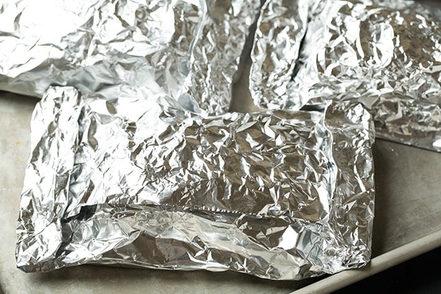 Baked Salmon and Asparagus in Foil Wrapping salmon in foil packets and setting on baking sheet to bake.