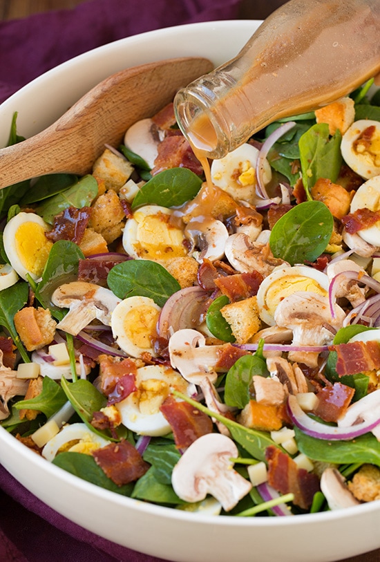 Spinach Salad with Warm Bacon Dressing in a white bowl 