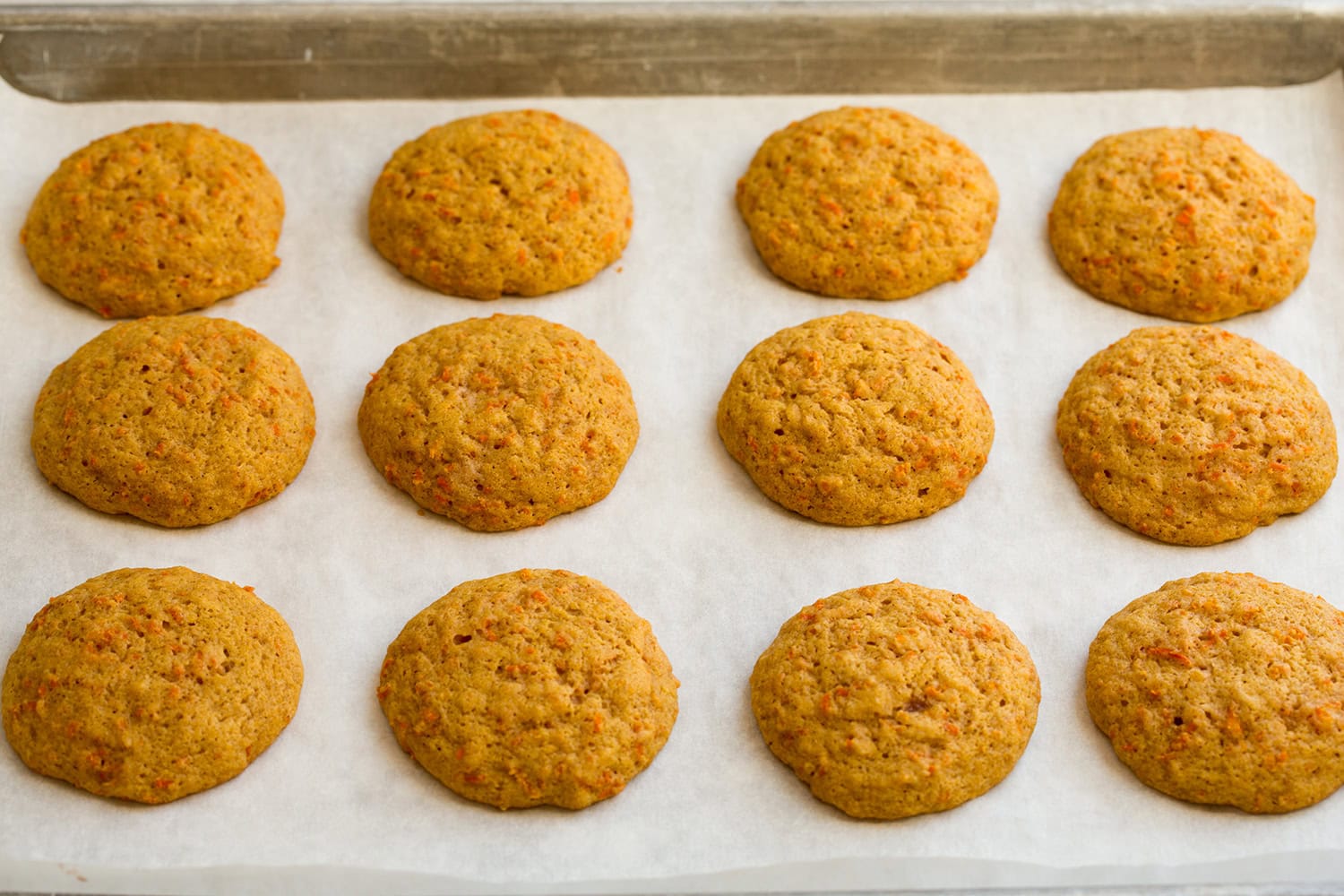 Carrot cake cookies shown after baking on baking sheet.
