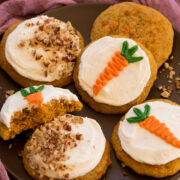 Plate of carrot cake cookies with decorations and pecans on frosting.