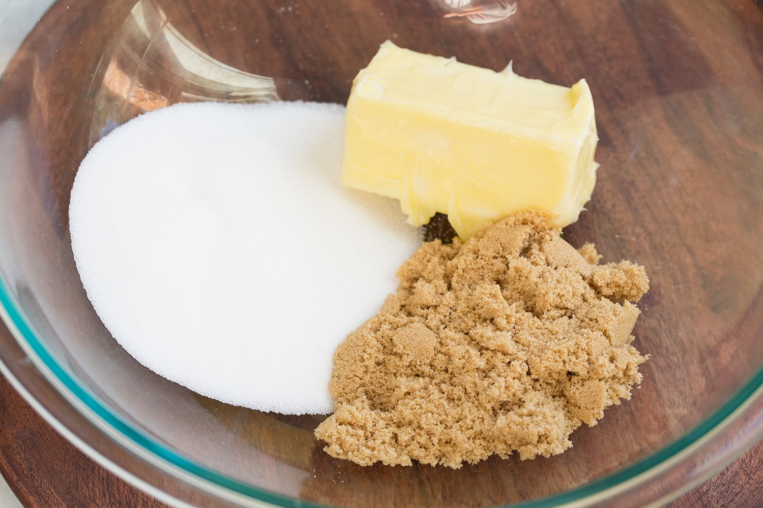Brown sugar, white sugar and butter in a glass mixing bowl.