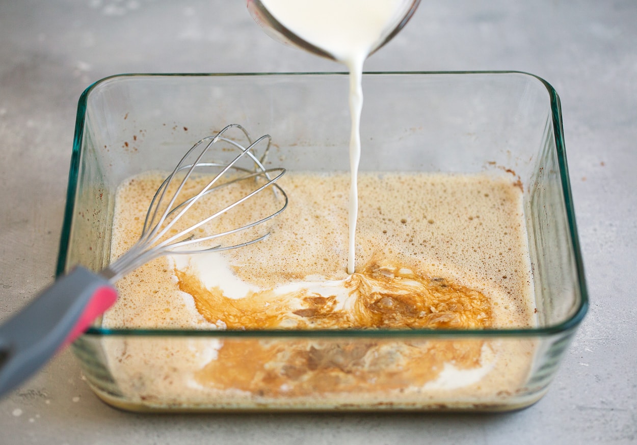 Adding milk and cream to french toast custard mixture.