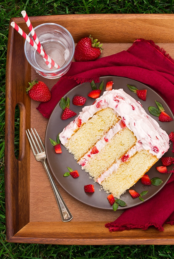 slice of Fresh Strawberry Cake on a plate with a fork and glass