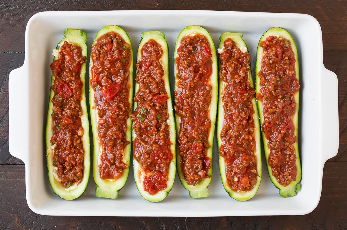 Adding sauce layer to zucchini boats.