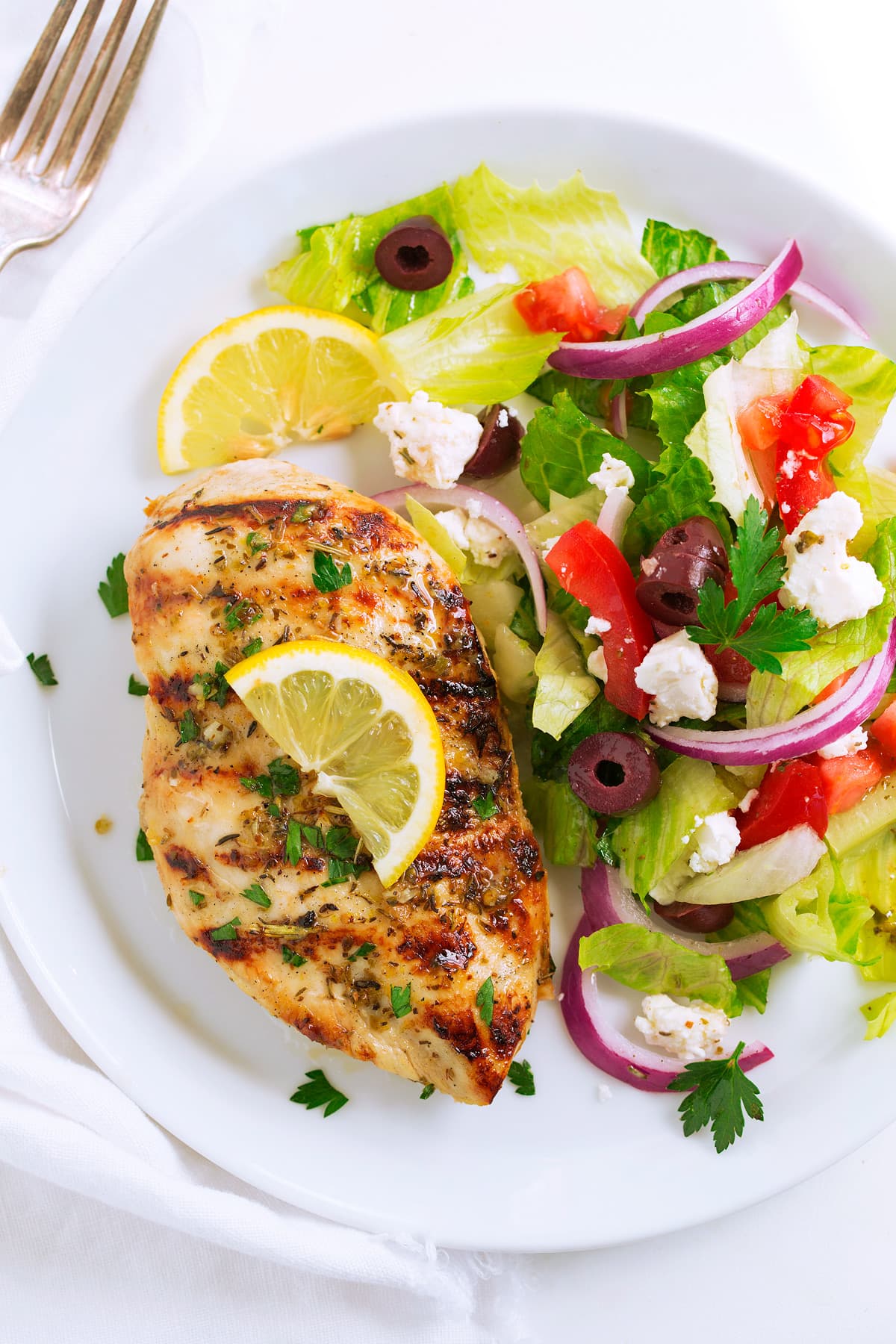 Greek lemon chicken with a side salad on a serving plate.