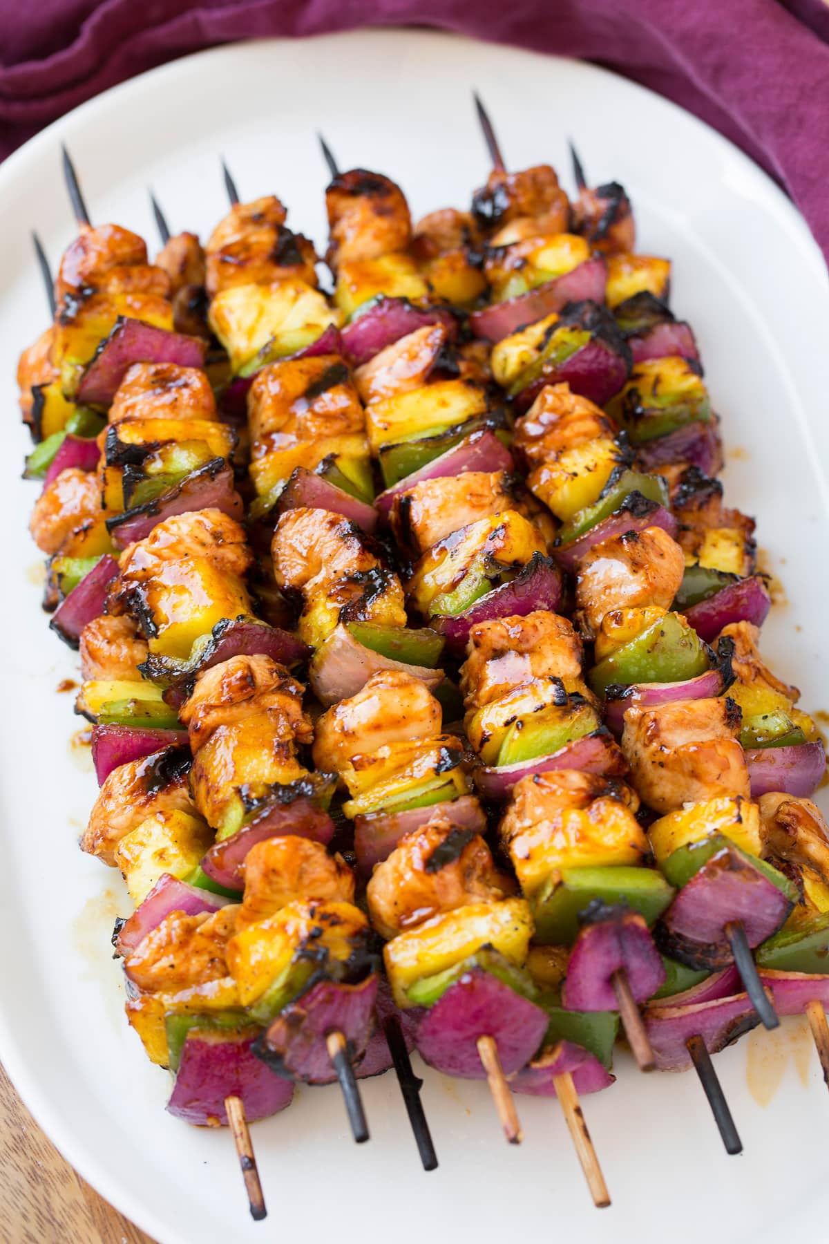 Marinated hawaiian chicken skewers on a white serving plate.