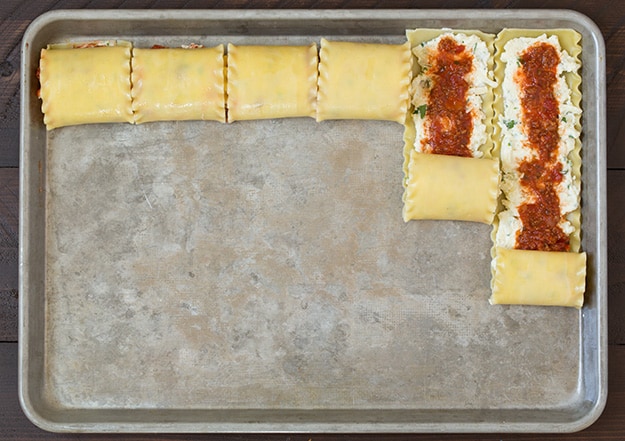 Lasagna Roll Ups on a baking tray getting rolled up